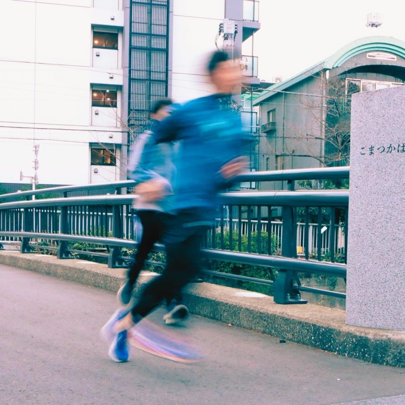 Men are running in front of bridge